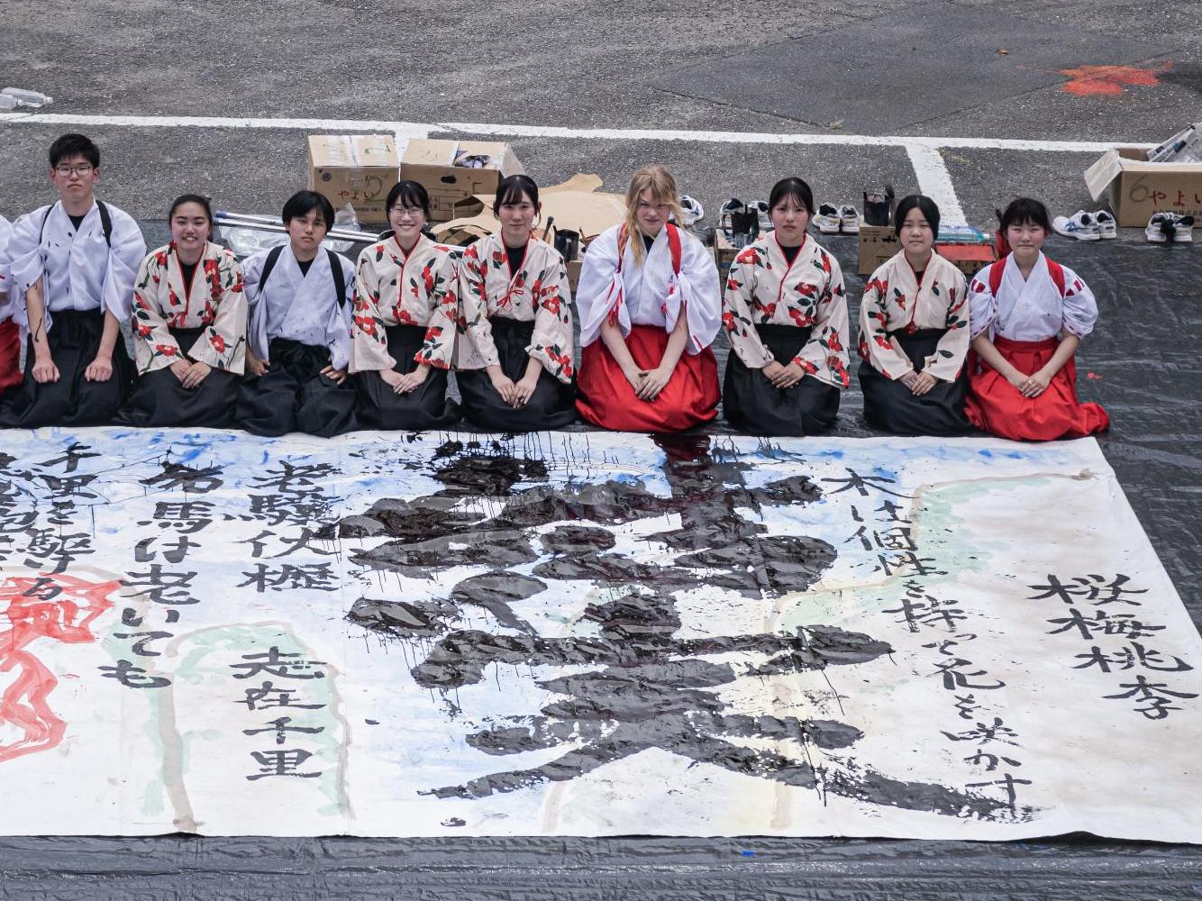 校庭に広げた大きな半紙に書道の作品を描いた様子