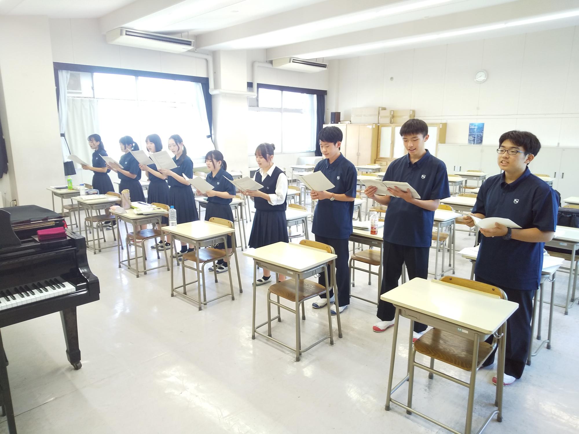 9人の学生が1列に並んで合唱する様子