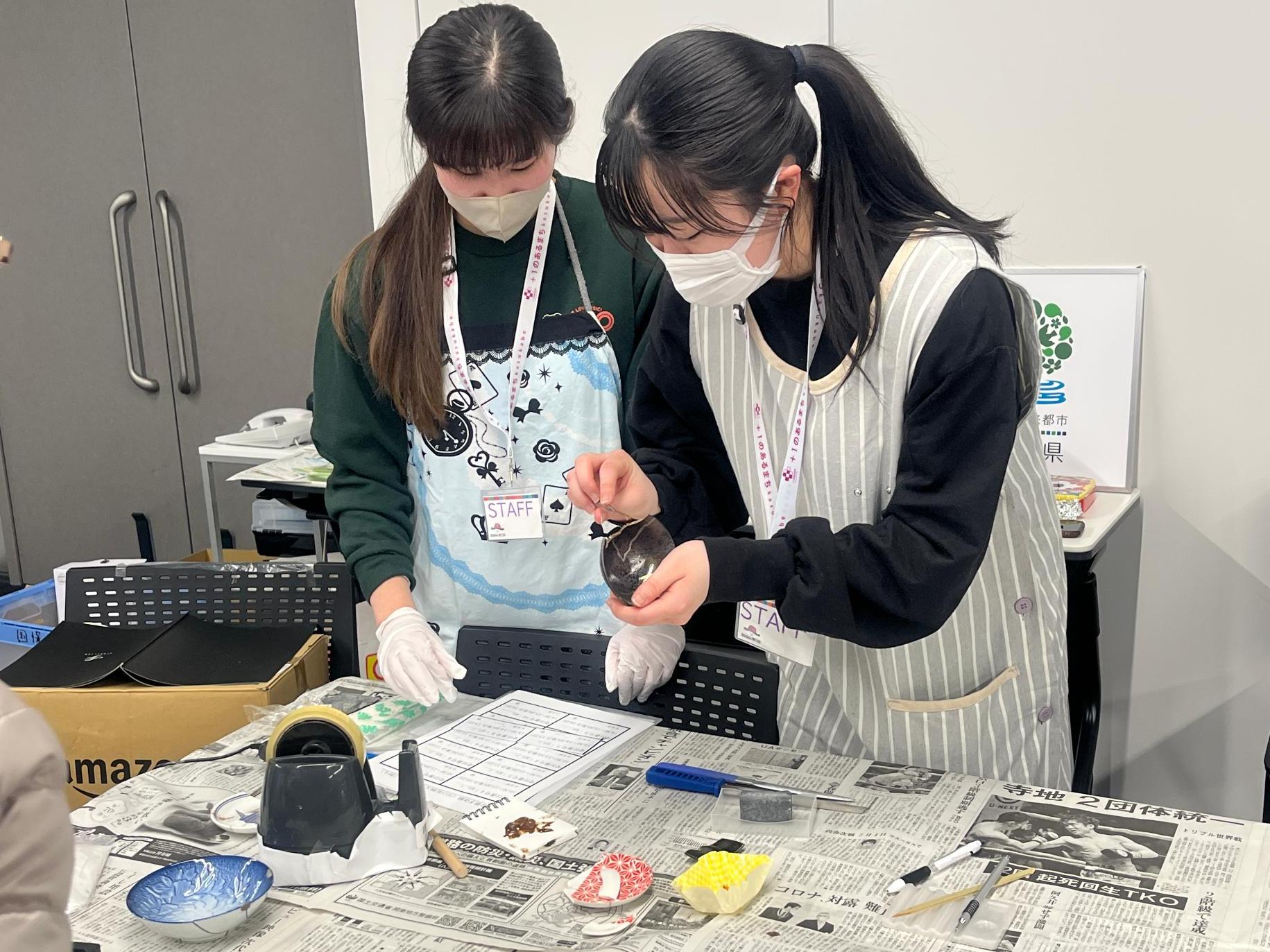 学生スタッフが割れた陶器の接合作業をする様子