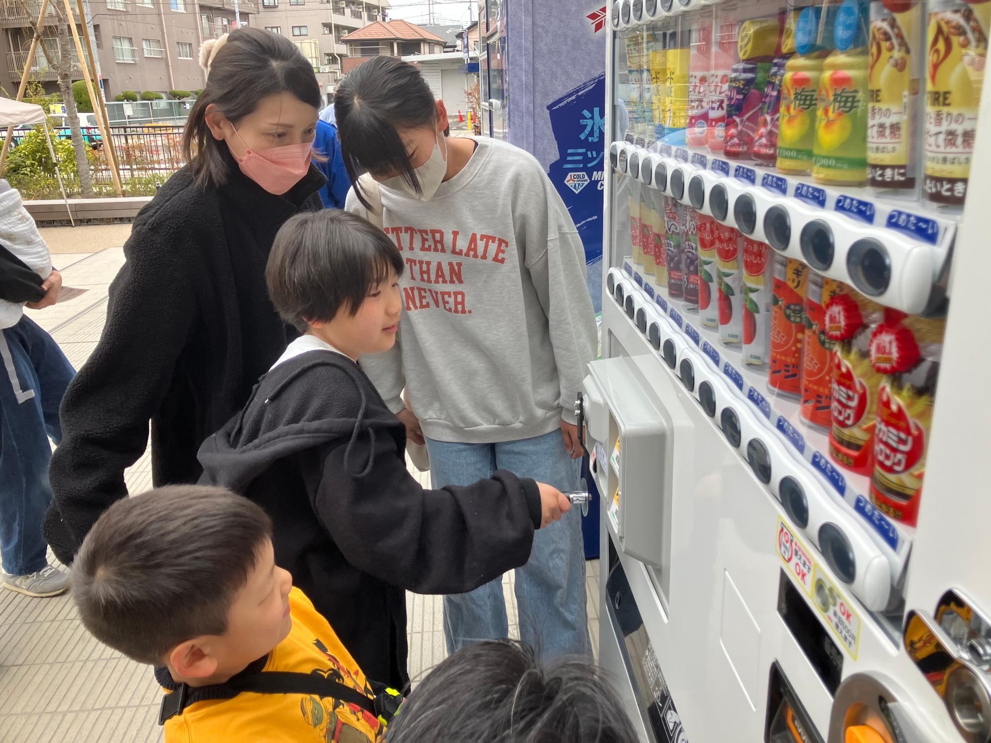 こどもが自動販売機のハンドルを回して発電する様子