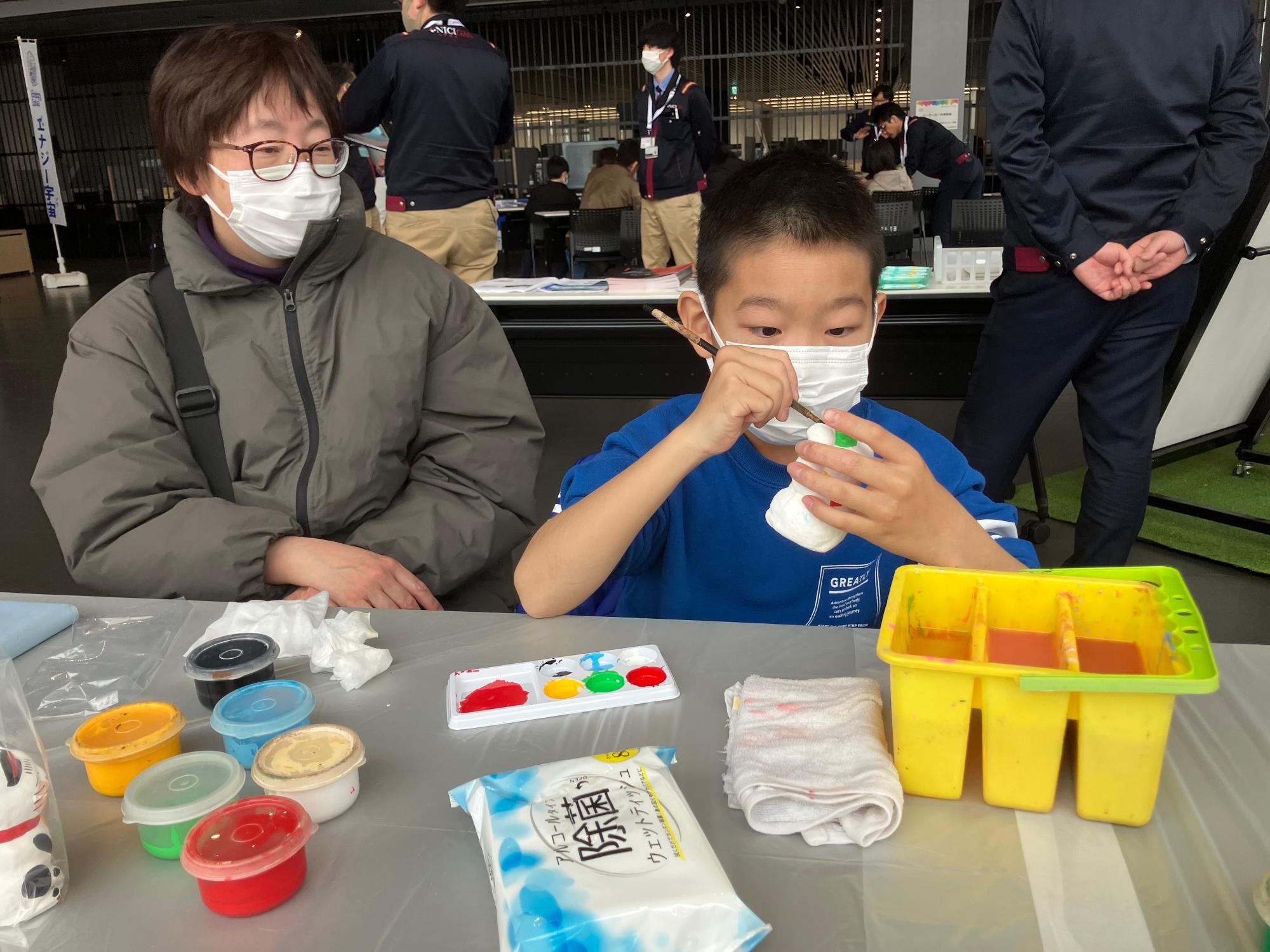 こどもが招き猫に絵の具で色をつける様子