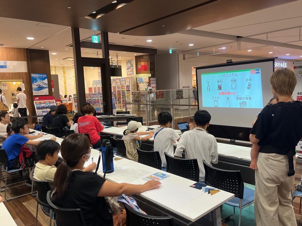 小中学生が10名ほど、スクリーンを観ながら授業を受ける様子