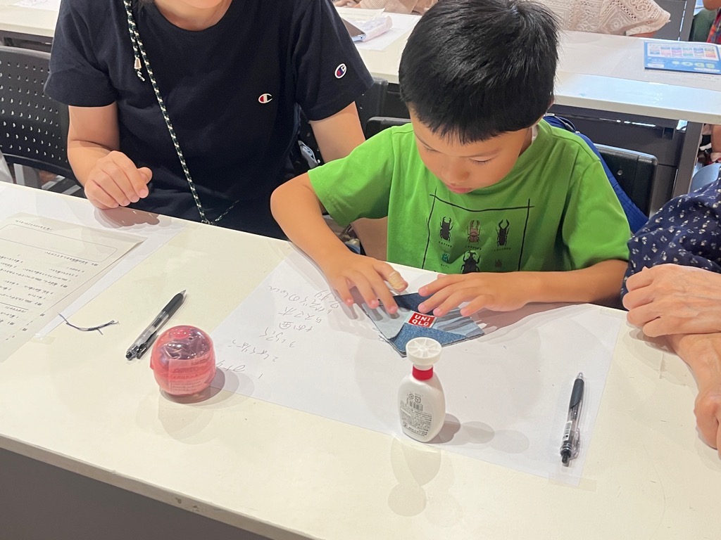 男の子がハギレを接着剤を使い組み合わせる様子