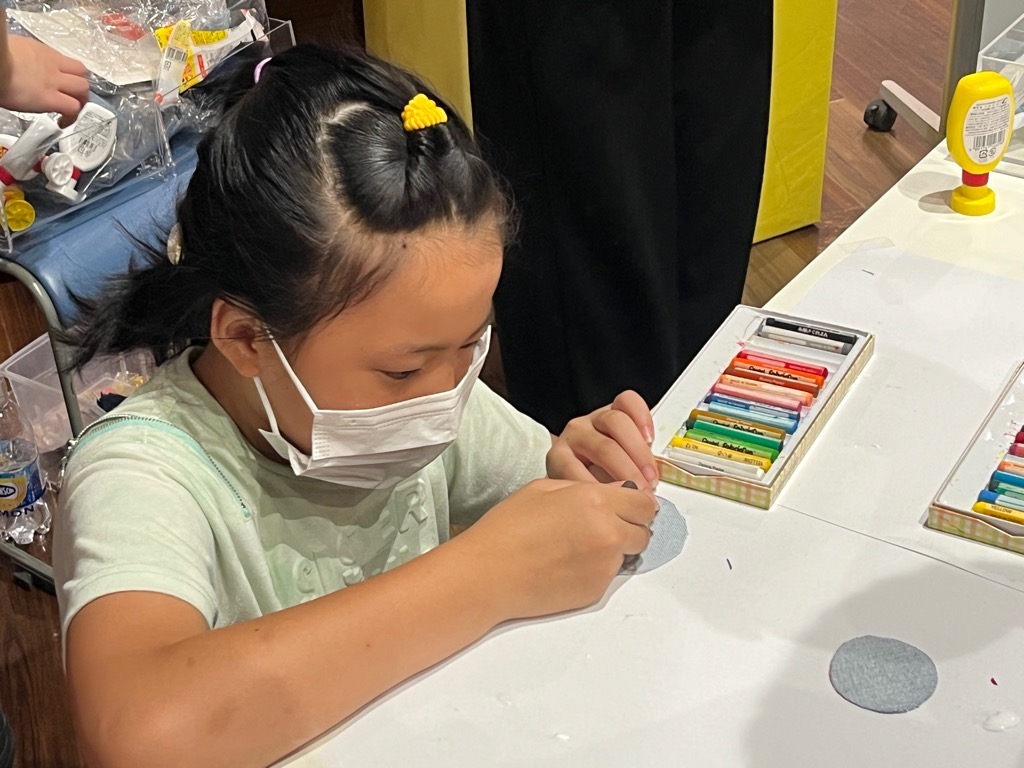 女の子がハギレにクレヨンで絵を描く様子