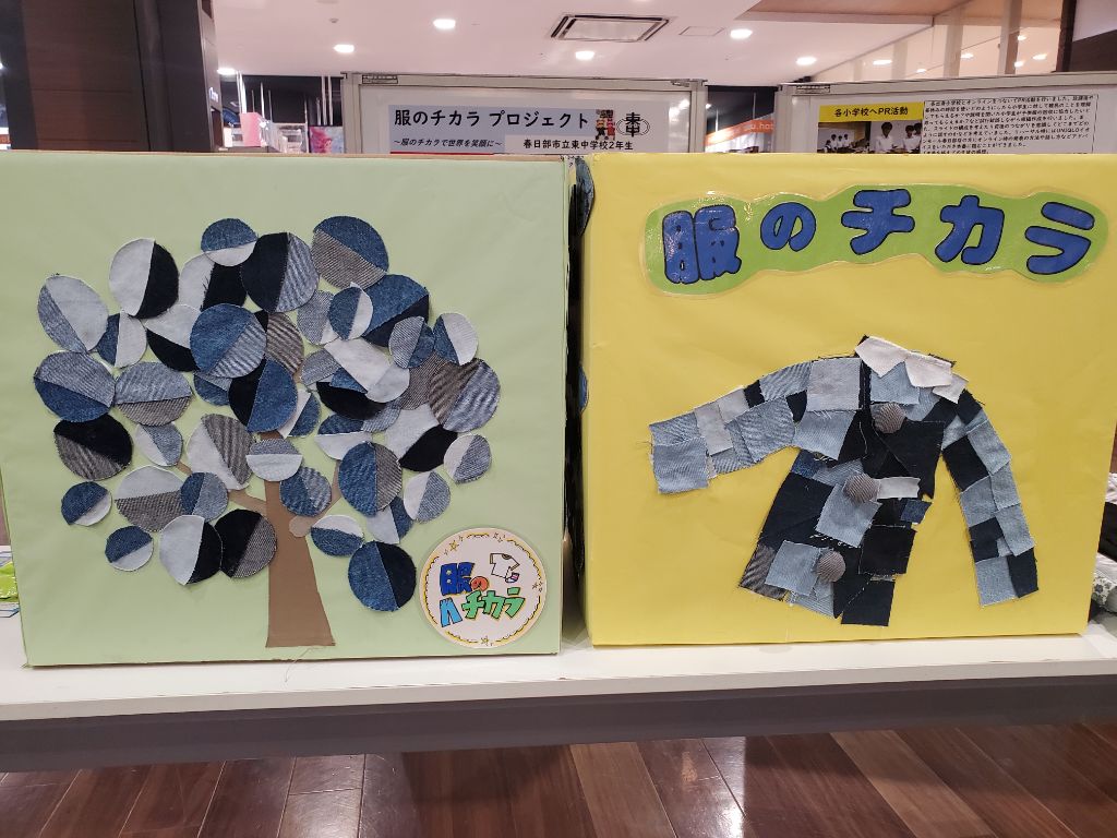 こどもたちがアレンジした服の回収ボックスが2個、机の上に置いてある写真