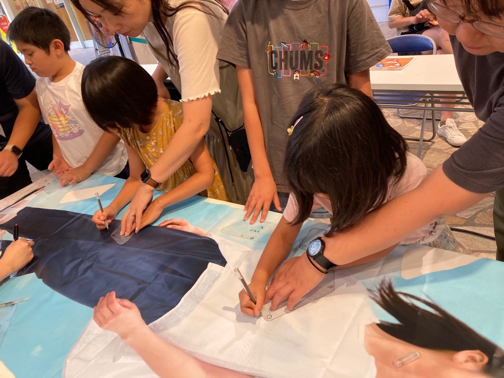 机に敷かれた店舗バナーに好きな部分を鉛筆でマークする様子