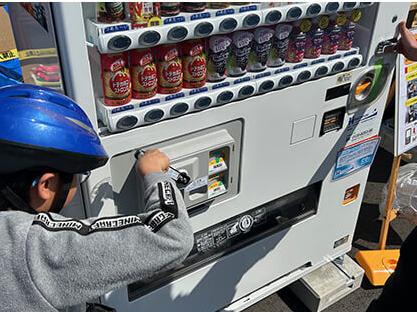 男の子が自動販売機でハンドルを回す様子