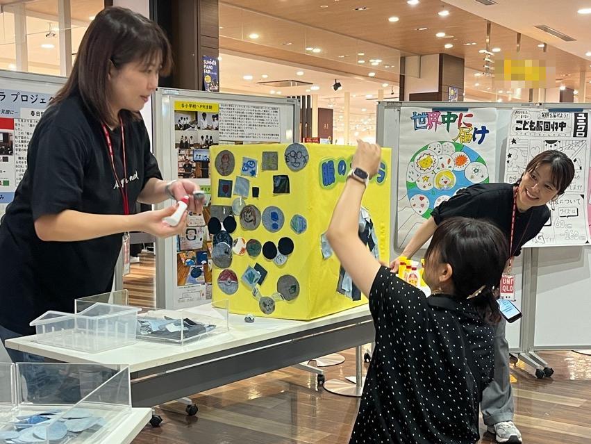 ユニクロスタッフ3名が完成した服の回収ボックスを最終調整する様子