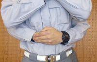 両手で抱えるようにみぞおちのあたりを押さえている写真