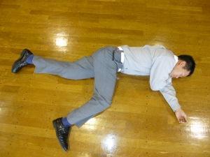 フローリングに横向きに倒れている人の写真