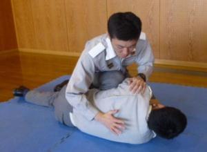 マットに横向きに寝かされて背中を叩かれる男性の写真