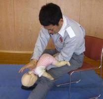 赤ちゃんの人形の頭部をを下にして支えている男性の写真