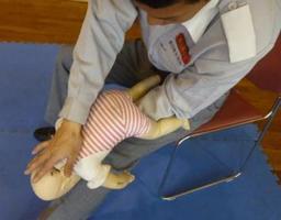 頭を下に支えられて背中を叩かれる赤ちゃんの人形の写真