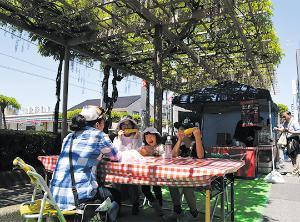 藤棚の下にクロスの敷かれたテーブルとイスが設置されている藤テラスの写真