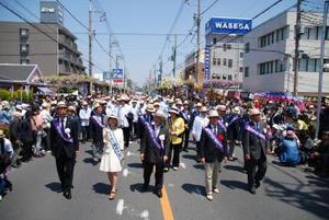 タスキを肩にかけた親善大使たちが並んで練り歩く写真