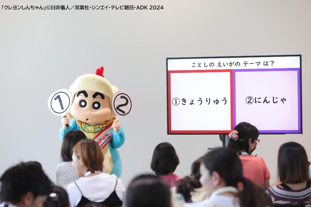 回答札を顔の横に持っている、恐竜姿の野原しんのすけくん