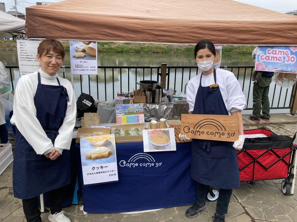 出店の前でポーズをきめるcomecome30の店員さん