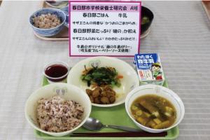 春日部ご飯など三皿のメニューと牛乳、デザートが並んだ給食の写真