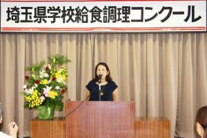 演台の前で立って話をする女性の写真