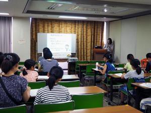 ホワイトボードに映写機で資料が映され、それを受講者が見て学習している写真