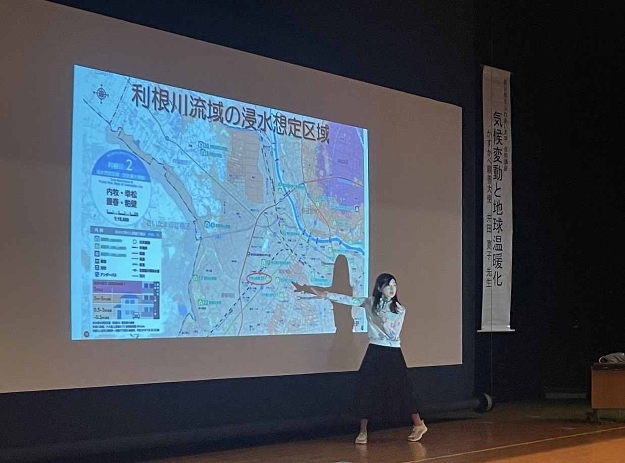 スクリーンの前で講演する井田大使