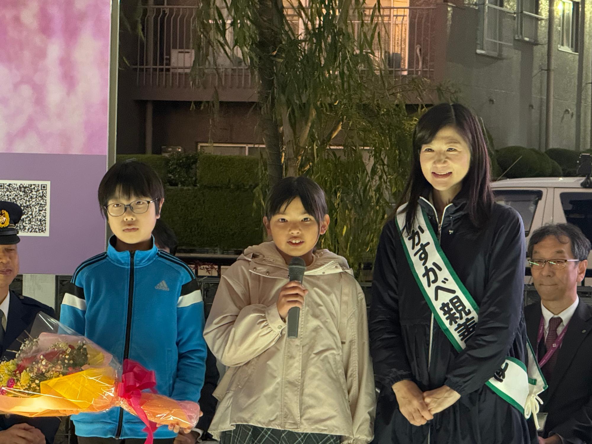 小学生と一緒に壇上に上がりスピーチをする井田大使