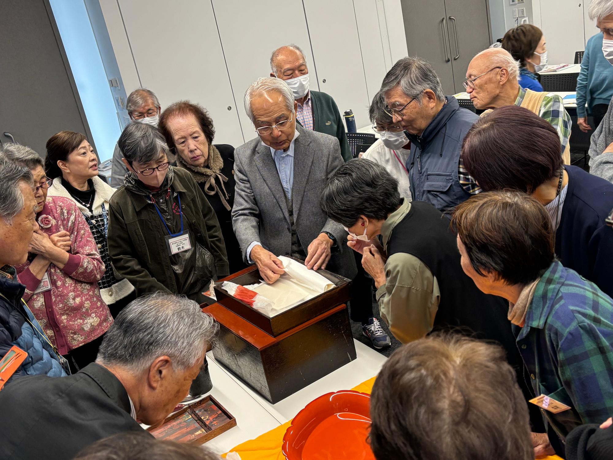 作品を見せる増村大使と熱心に見る受講生たち