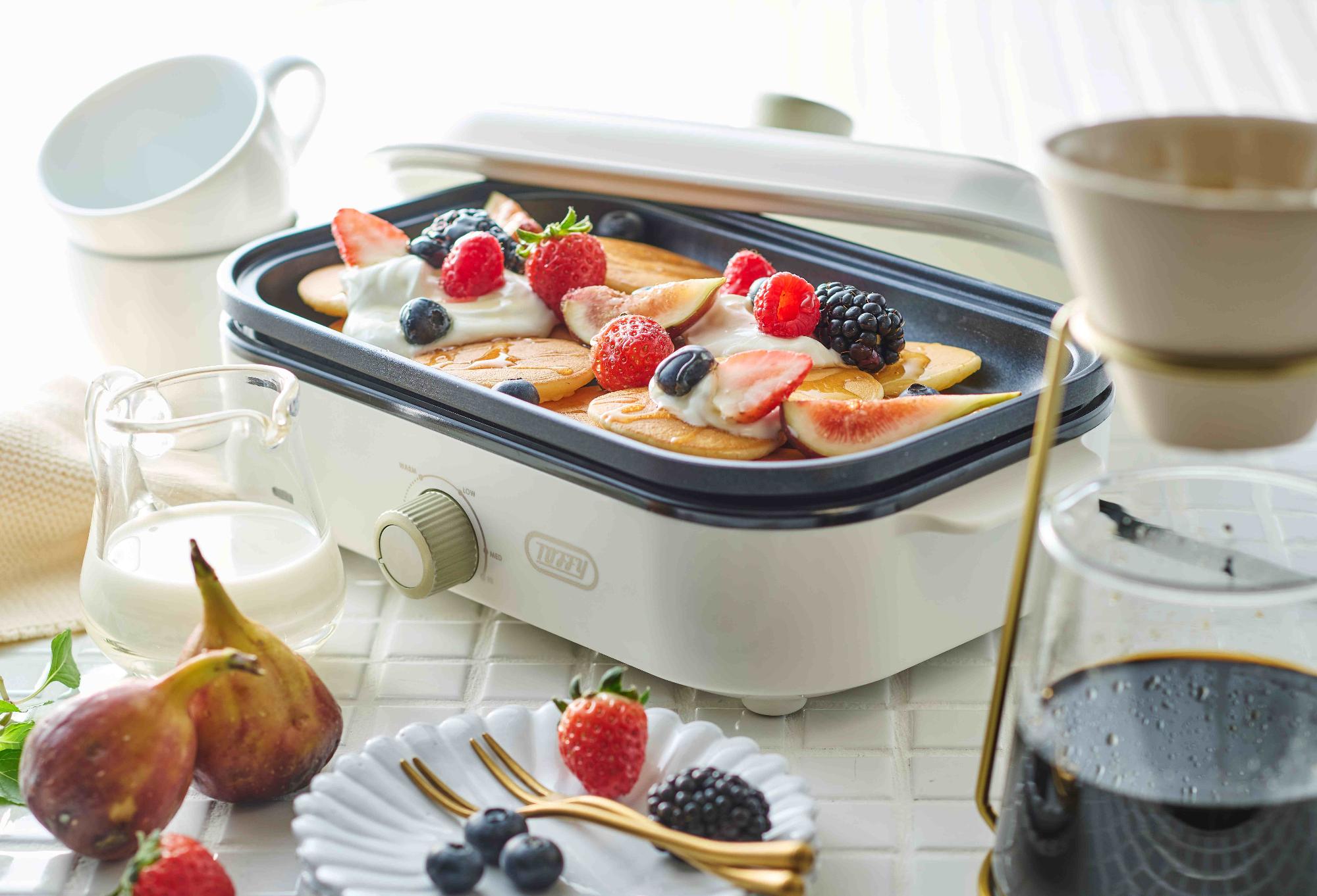 イチゴやブルーベリーなどがトッピングされたパンケーキが乗ったホットプレートの写真
