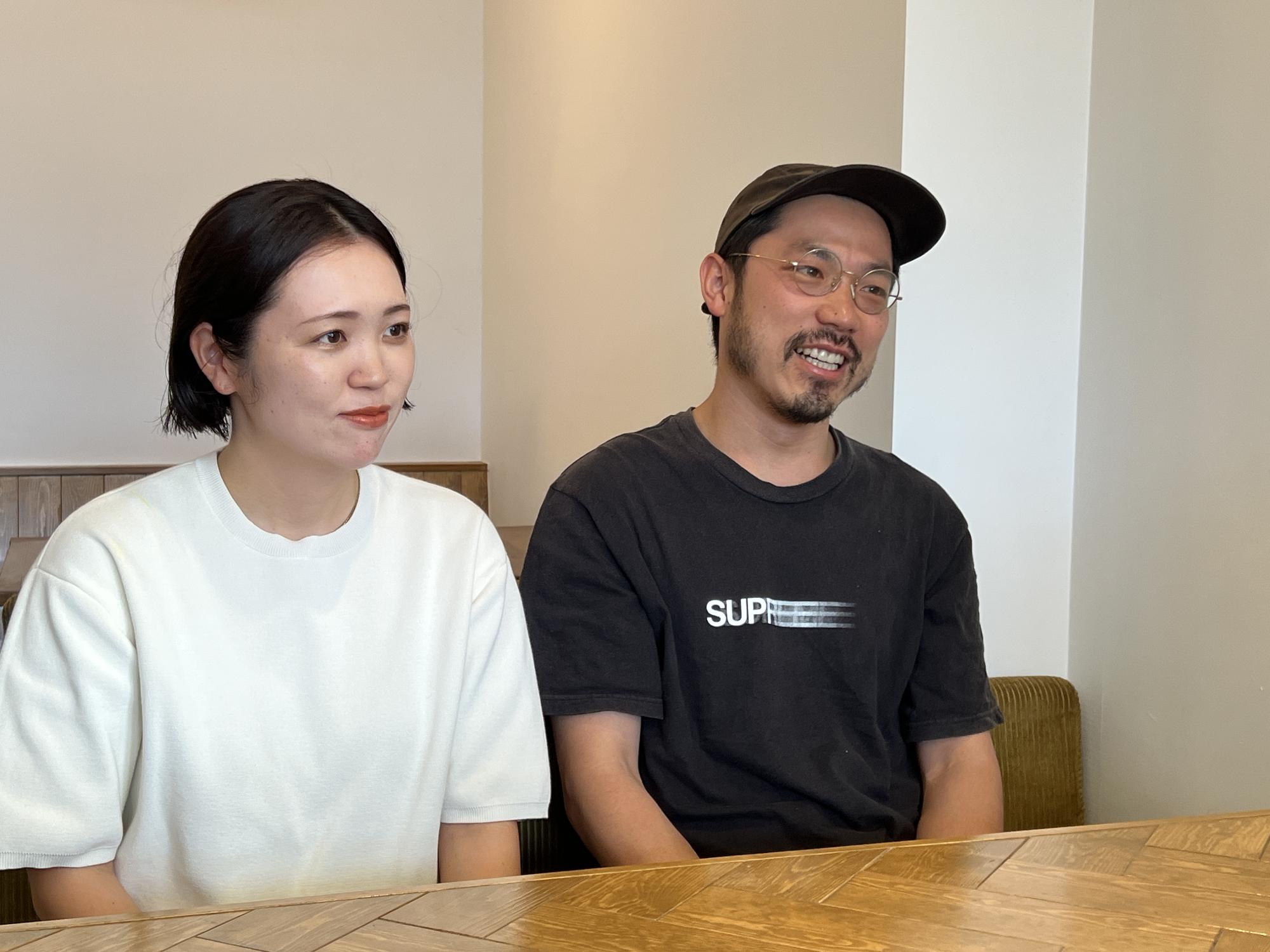 インタビューを受ける白いTシャツを着ている響さんと黒いTシャツを着て黒い帽子をかぶっている良平さんの写真
