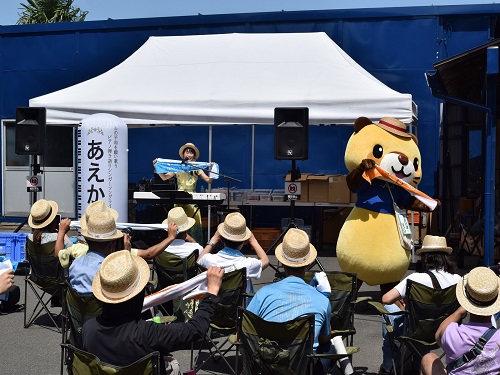 かすかべ親善大使のあえかさんのライブでは、観客と一緒にタオルを両手に広げて盛り上がっています。北春日部きゅうのすけくんも参加しています。