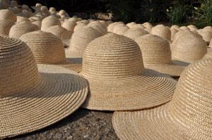 沢山の麦わら帽子がつばの部分を重ねるようにして並べられている写真