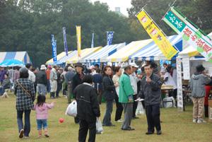 黄色と青色のテントとのぼりが並び、多くの人が集まっている写真