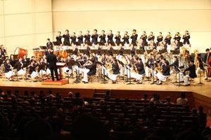 舞台の上で、白と黒の衣装を着たオーケストラの人たちが演奏している写真