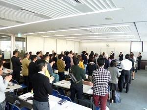 市の職員と参加者たちが立ち上がって拍手をしている写真