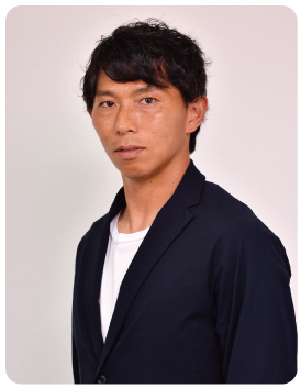 黒色のスーツに白いTシャツを着て正面を見ている佐藤 寿人さんの写真