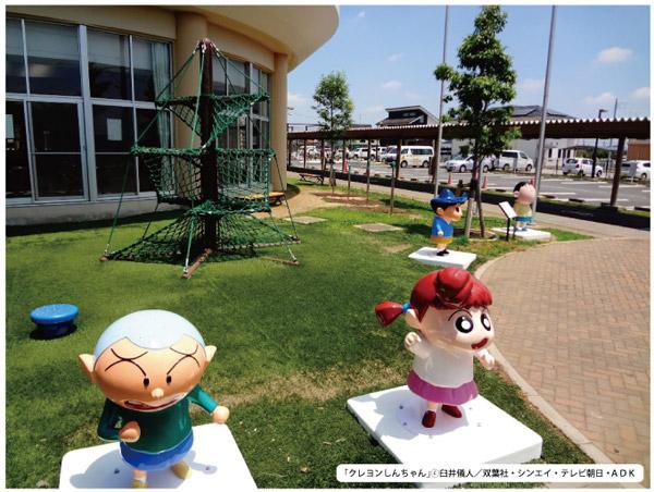 クレヨンしんちゃんのマサオくん、ネネちゃん、風間くん、ボーちゃんのモニュメントが、芝生の上に並んでいる写真