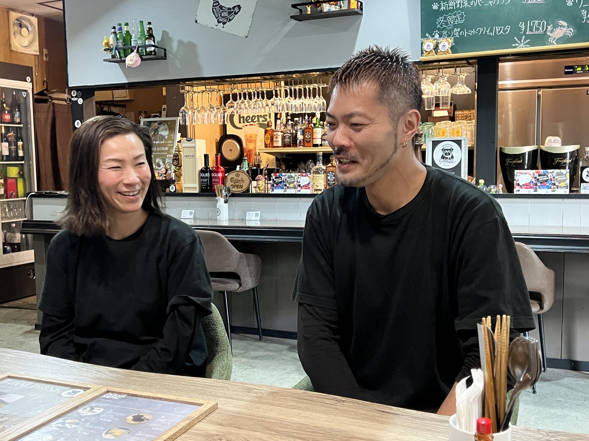 店内のテーブル席に座り、笑顔でお話しする五嶌弘太郎さんと真理さん