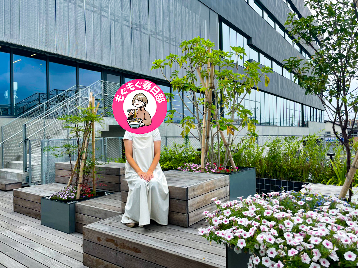 ひだまりテラスに座ってカメラに写るもぐもぐ春日部さん