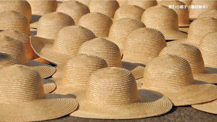 つばの部分を重ね合わせるようにして麦わら帽子が並べられている写真