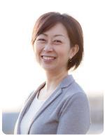 薄紫のジャケットを着た鈴木美緒さんが、こちらに向かって微笑んでいる写真