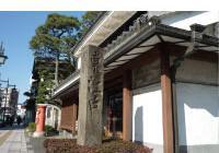 和風建築の前に、石でできた長細い柱が建っている写真