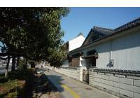 歩道に沿って、瓦屋根がある土蔵造りの建物が並んでいる写真