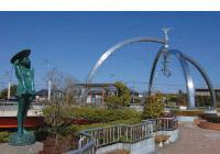 奥に銀色をした弓型のモニュメントが建っている、公園の写真