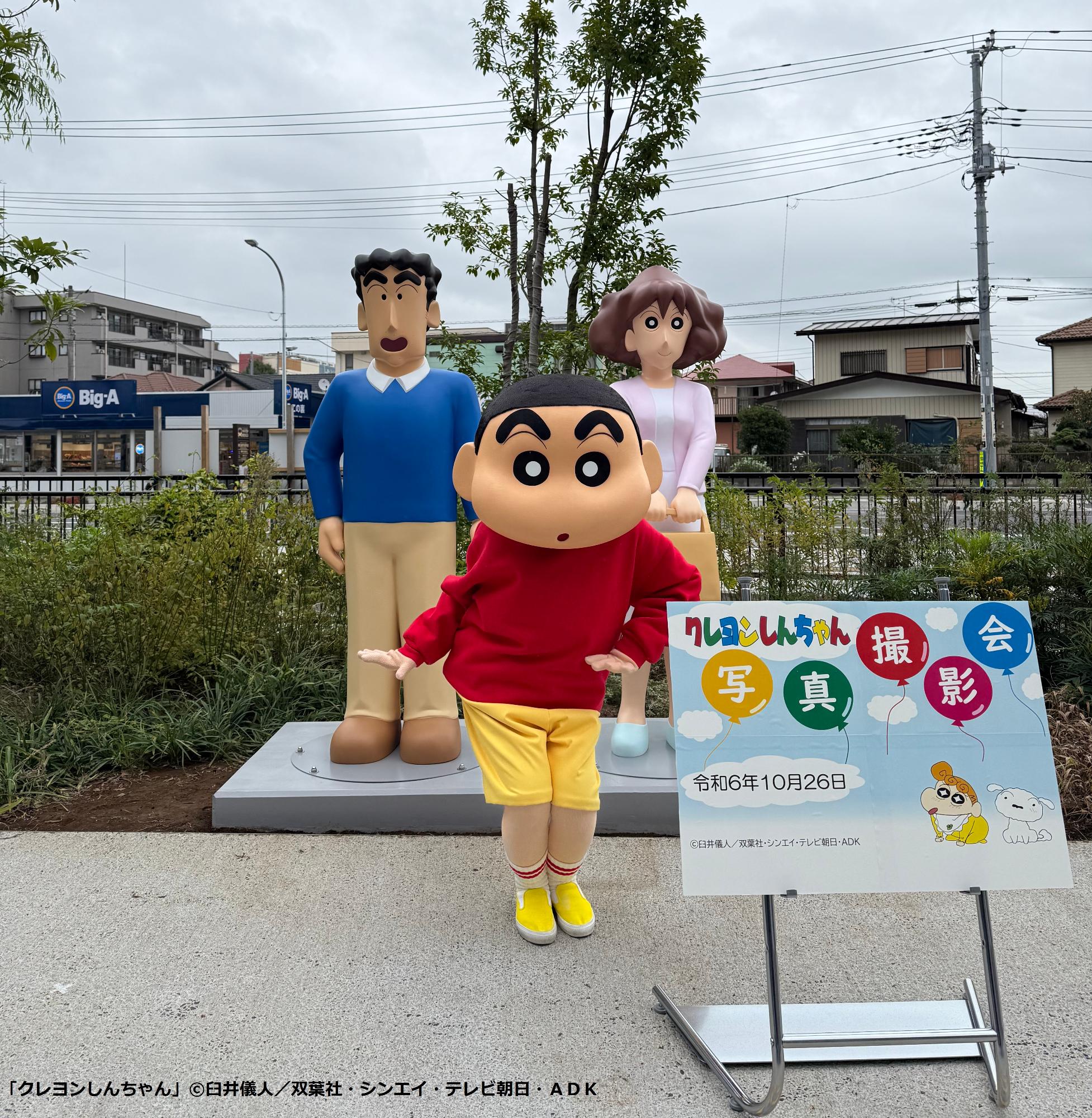 お披露目されたモニュメントの前でポーズをしている野原しんのすけくんの写真