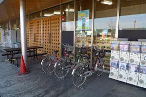 ガチャガチャの台と自転車が並んでいる建物の入り口の写真