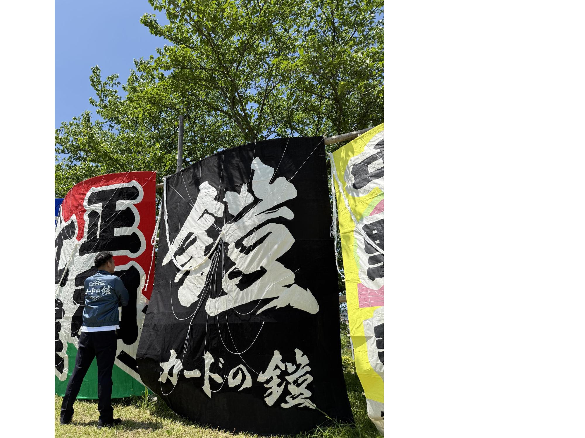 鎧と書かれたコマーシャル凧の前に立つ鈴木俊介さん