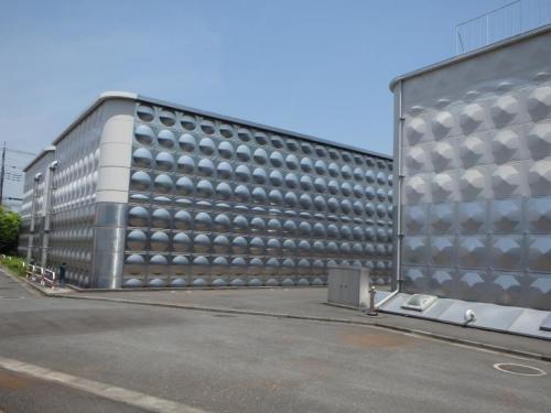 青空の下に建つ外壁一面に球体の突起物がある巨大な配水池タンクの外観を撮影した写真