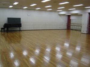 フローリングの床で奥にピアノがあるリハーサル室の写真