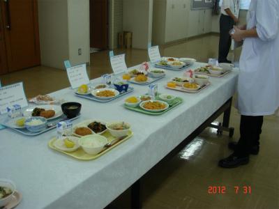 長机に複数の献立が載ったお盆が並び審査されている様子の写真