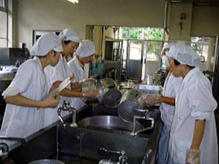 食缶を洗いながら指導や話し合いを行う人たちの写真